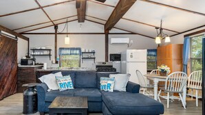 A cozy living area with a sofa, a dining table, and a kitchen in the background.