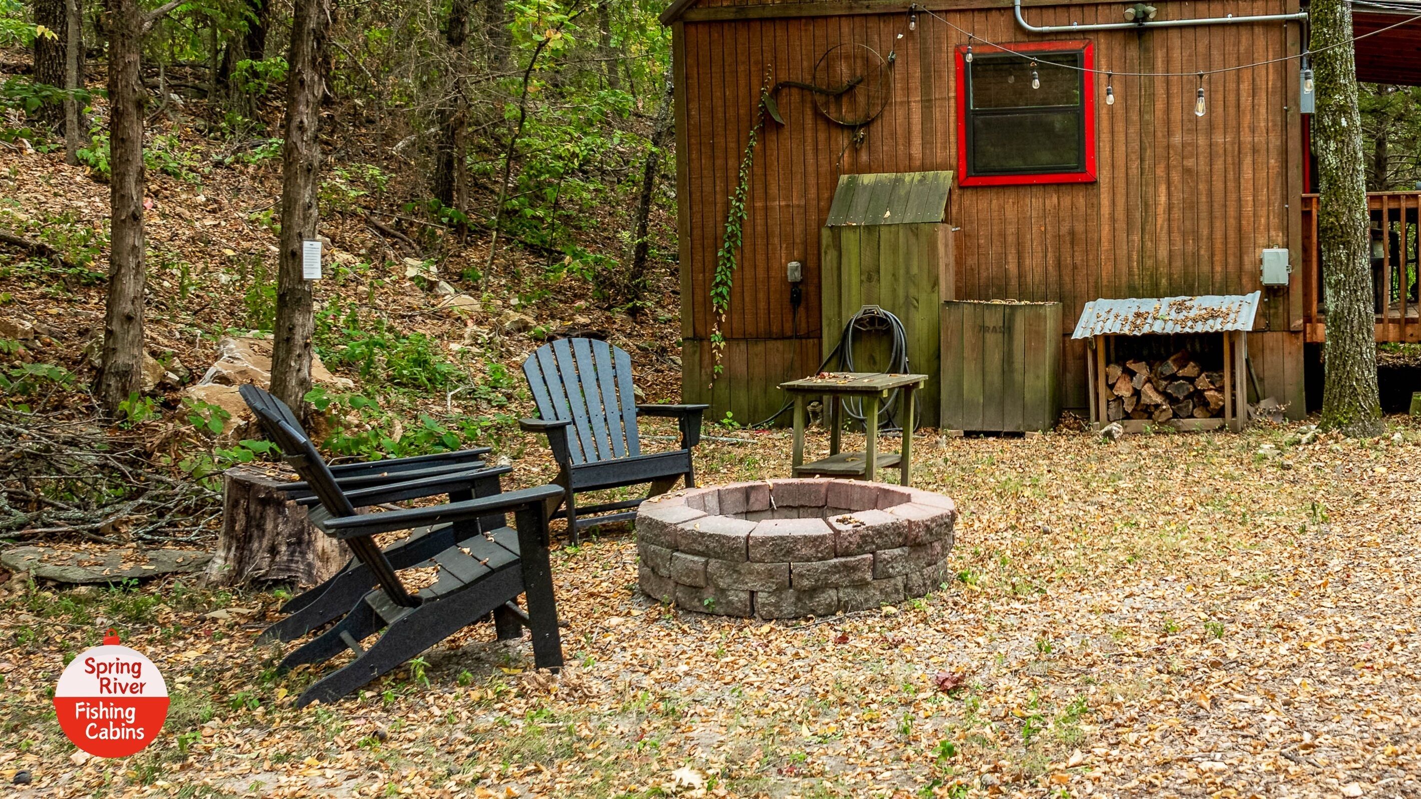 A rustic cabin with a fire pit, two Adirondack chairs, and a small table.