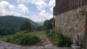Un chemin de pierres mène à un bâtiment rustique doté d’un mur en pierre et d’une porte en bois.