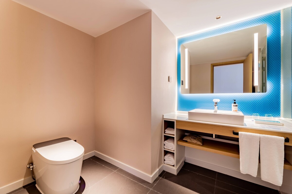 A modern bathroom with a toilet, sink, and mirror.