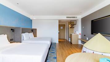 A hotel room with two beds, a TV, a minibar, and a view of the cityscape.