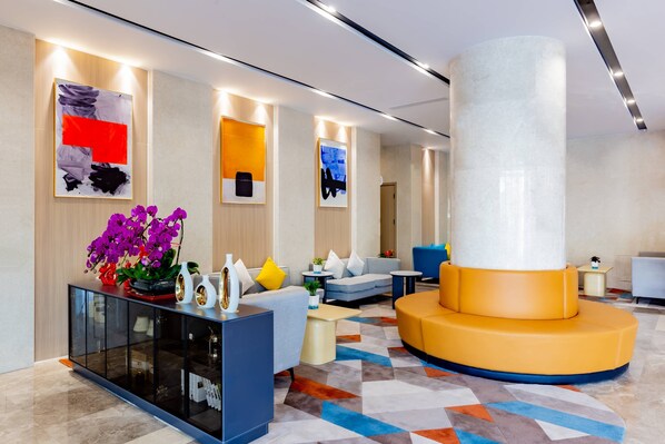 A modern lobby with a central seating area, a glass cabinet with decorative items, and artwork on the walls. - Holiday Inn Express Hohhot East Station by IHG (Hohhot)