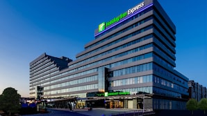 Un moderno hotel Holiday Inn Express con un cartello ben visibile, diversi piani e una facciata in vetro.