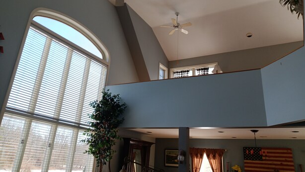 Un intérieur spacieux avec de hauts plafonds, de grandes fenêtres et un ventilateur de plafond.