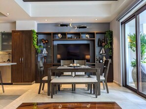 A modern dining area with a large flat-screen TV, dark wood cabinetry, and a dining table with chairs.