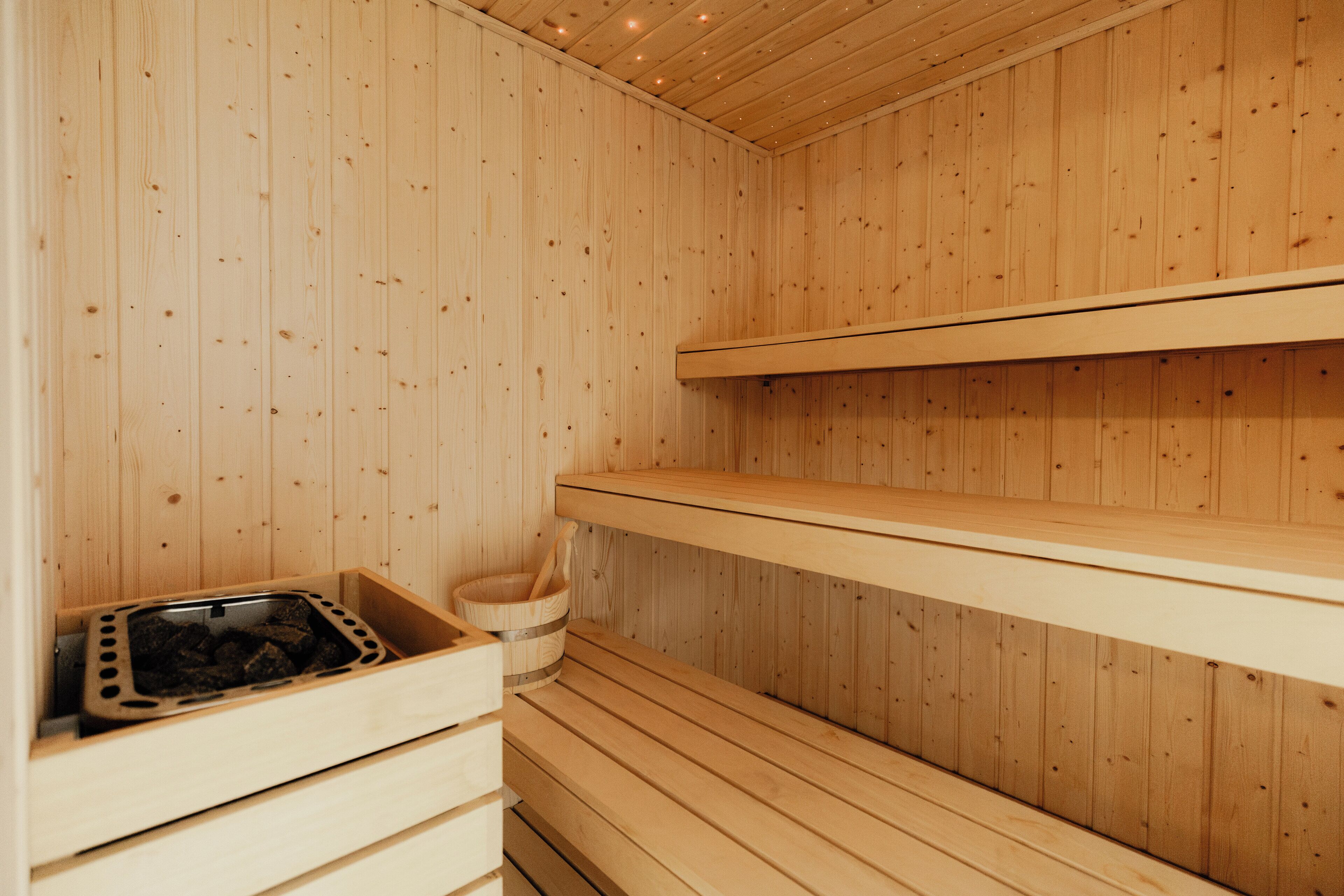 Una sauna de fusta amb seients i una safata de pedra.