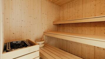 Una sauna de fusta amb seients i una safata de pedra.