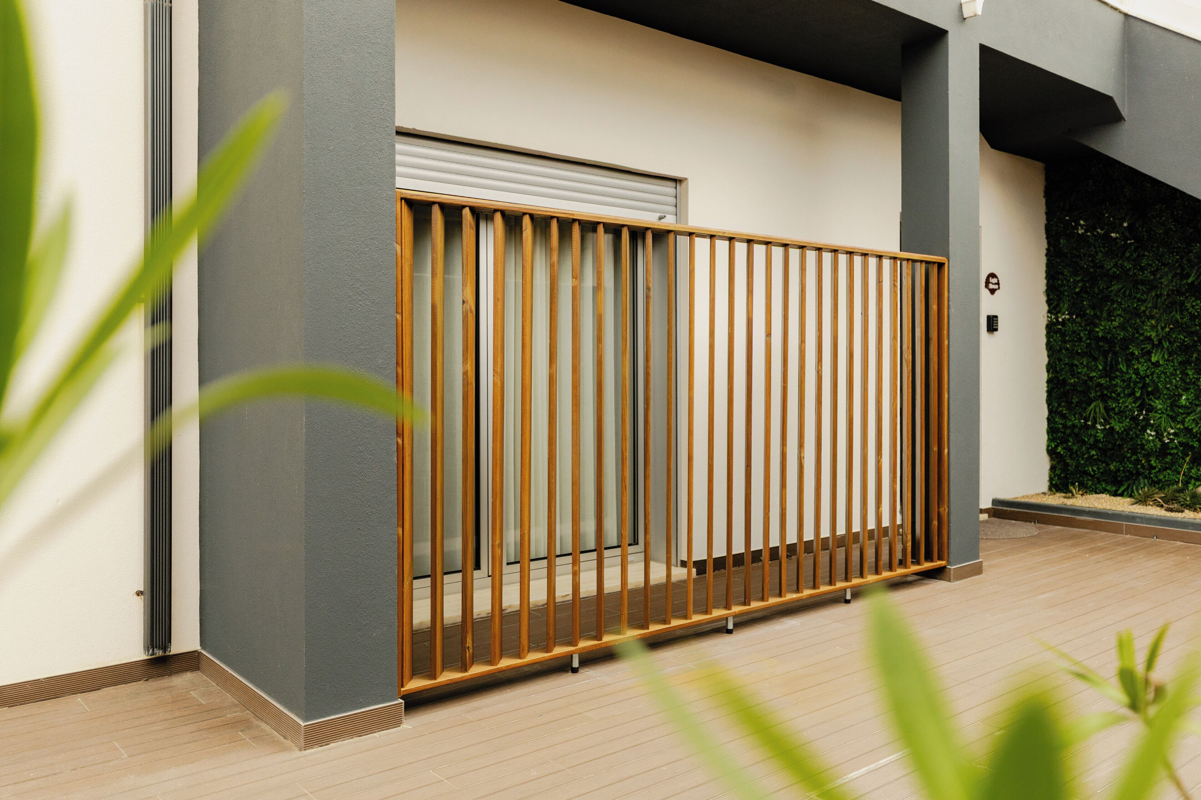 A modern building exterior with a wooden fence, a garage door, and a green hedge.