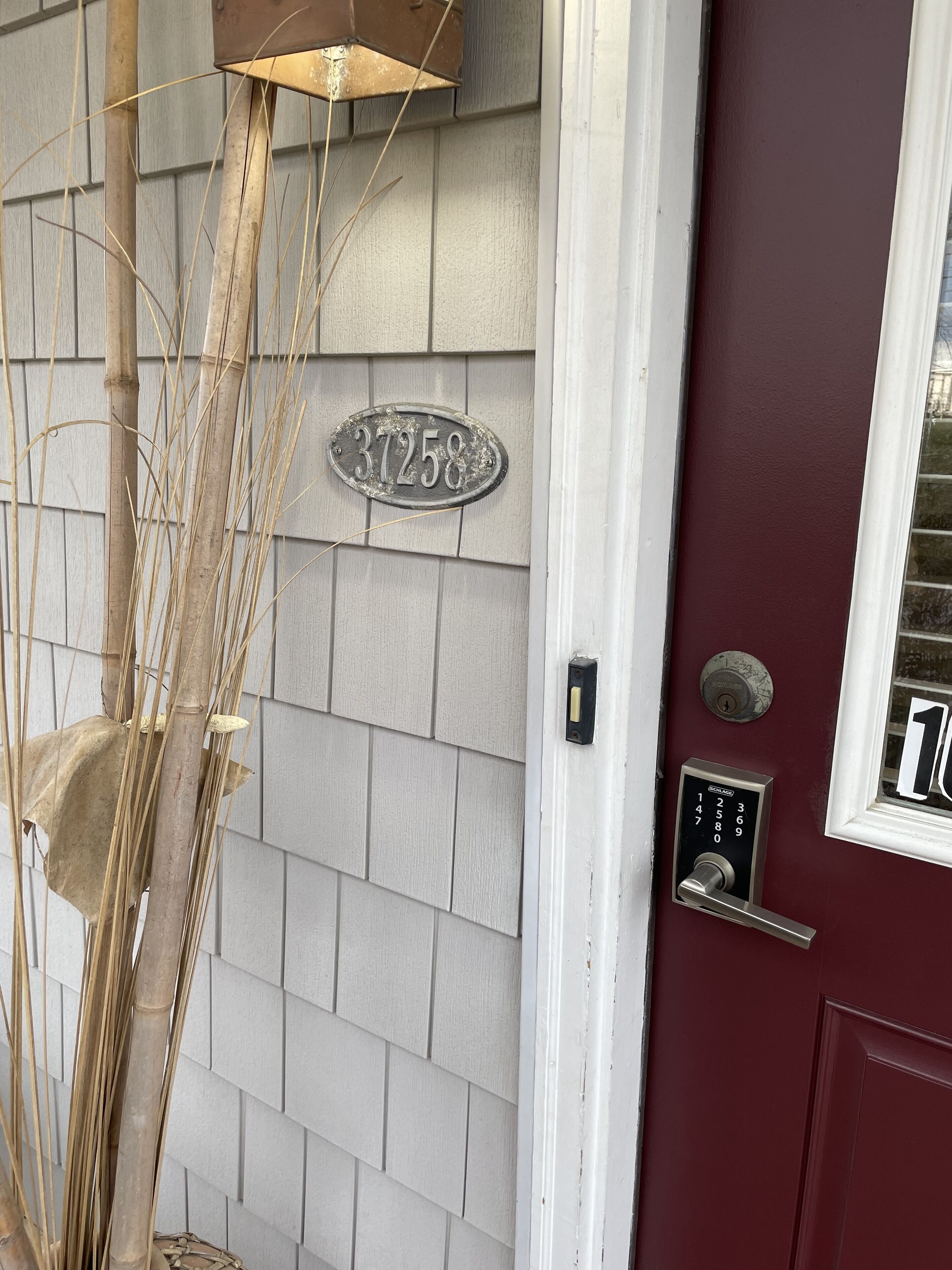 A house number 37258 on a light grey siding wall, a red door with a window, and a mailbox.