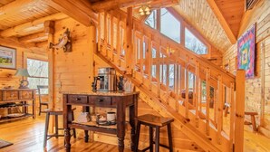 Un intérieur en bois avec un escalier, un coin café et une vue sur l’extérieur.