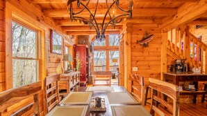 L’intérieur d’un chalet en bois comprend un coin repas, des murs en bois, un lustre et un poisson décoratif accroché au mur.