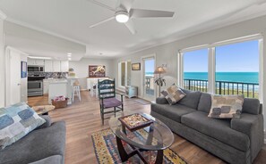 A spacious living area with a view of the ocean, a kitchen with modern appliances, and a dining area.