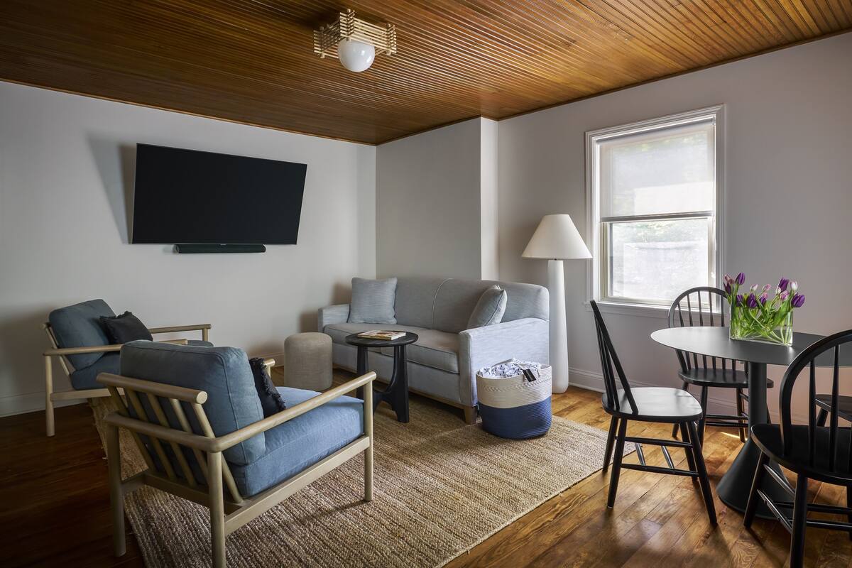 A modern living room with a sofa, armchair, coffee table, and dining table.