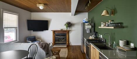 A modern kitchen with a wooden ceiling, a flat-screen TV mounted on the wall, and a built-in stove.