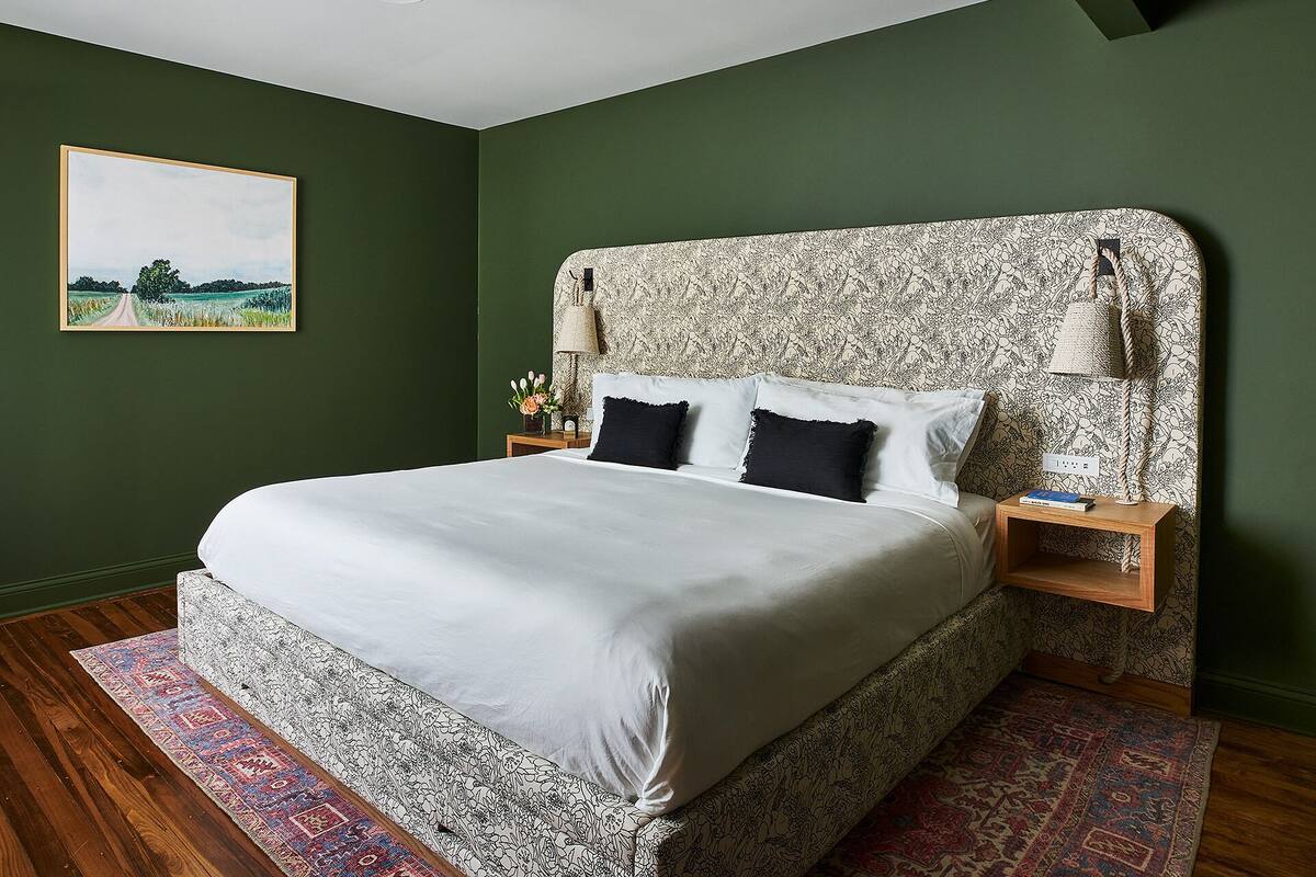 A neatly made bed with a patterned headboard, a bedside lamp, and a framed picture on the wall.