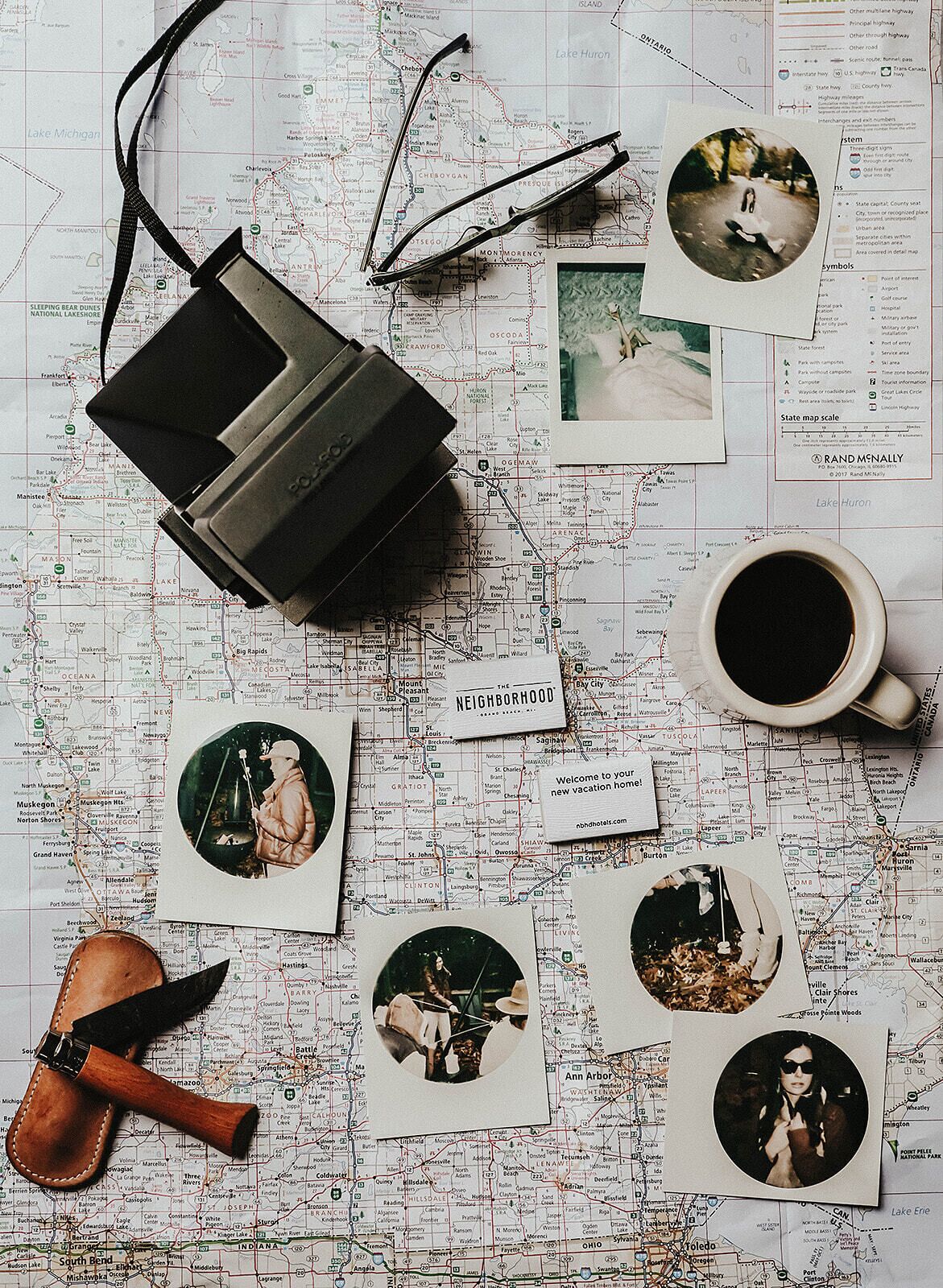 Une carte illustrée de divers objets liés au voyage, notamment un appareil photo ancien, une paire de lunettes, une tasse à café et des cartes postales représentant des personnes.