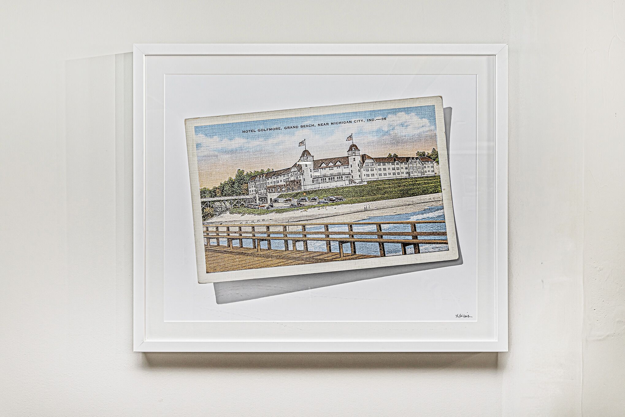 A framed illustration of a hotel with a waterfront view, including a pier and a large building with multiple flags.