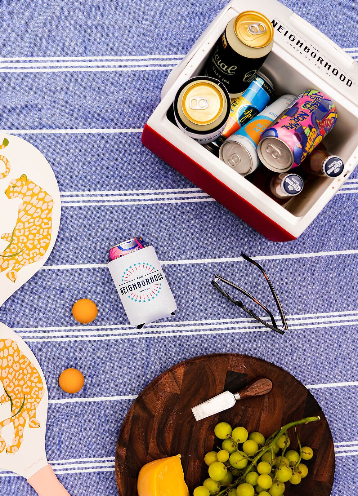 A tray with cans, a bottle, and a pair of glasses on a blue striped surface.