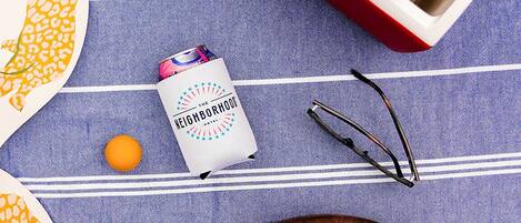 A tray with cans, a bottle, and a pair of glasses on a blue striped surface.