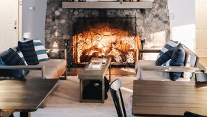Un salon chaleureux avec une cheminée en pierre, des meubles en bois et un mur d’accent en pierre.