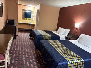 Une chambre d’hôtel avec deux lits, un bureau, une chaise, une salle de bain avec un miroir et une télévision.