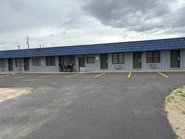 Un motel avec une rangée de chambres, chacune dotée d’une porte et d’une fenêtre. Une moto est garée devant le bâtiment.