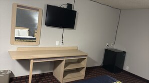Une pièce comprenant un bureau en bois, un miroir, une télévision et un petit meuble de rangement.