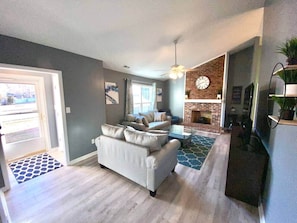 A living room with a sofa, a coffee table, a fireplace, and a door leading outside.