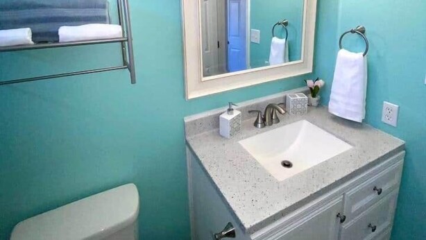 Une salle de bain comprenant des toilettes, un lavabo, un meuble-lavabo et un miroir.