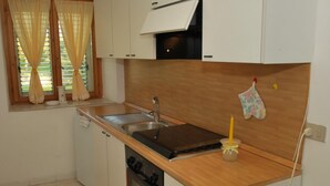 A compact kitchen with a sink, stove, and oven, wooden countertop, and a window with curtains. - Dante Pino in Tocco da Casauria (Tocco da Casauria)