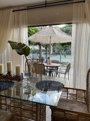 A glass-top dining table with wicker chairs, a woven placemat, and three candles. - Florida Keys Chic (Islamorada)