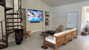 Una sala moderna con escalera de madera, un televisor de pantalla plana grande, un sofá y una mesa de comedor.