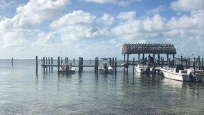 Un muelle con barcos amarrados, una estructura de techo de paja y agua cristalina.