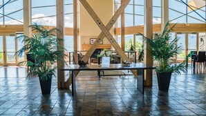 Un vaste espace intérieur doté d’un haut plafond, de grandes fenêtres et d’une structure centrale en bois.