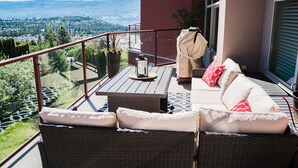Un balcon agrémenté de meubles en osier, d’une table et offrant une vue sur un paysage montagneux.