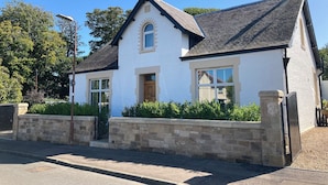 A two-story house with a white exterior, a brick chimney, and a stone wall in front. - ISLAY House, Comfortable home- private garden, in quiet village, near Edinburgh (Pencaitland)