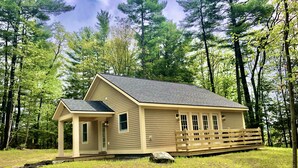 A single-story cabin with a gabled roof, a front porch, and a small deck area.