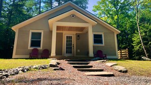 A small, single-story cabin with a front porch, two windows, and a door.