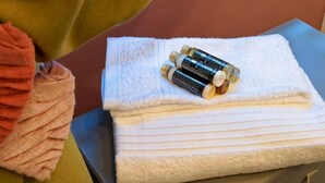 Une pile de serviettes blanches est posée sur une commode, avec trois bouteilles dessus.