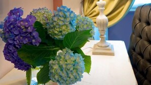 Une table blanche ornée d’un vase d’hortensias et d’une lampe blanche.