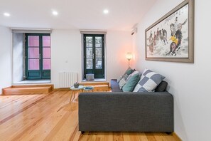 Relax in this stylish living room with a sofa, round table, and artwork, offering a view of the outside.