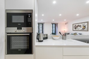 Enjoy cooking in this well-equipped kitchen with a microwave, oven, and kettle, offering a view of the outside.