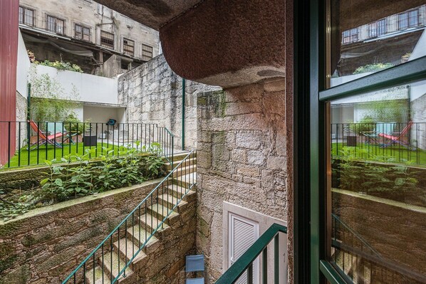 Residents enjoy a courtyard with a lawn and playground, surrounded by a low wall and metal railings.