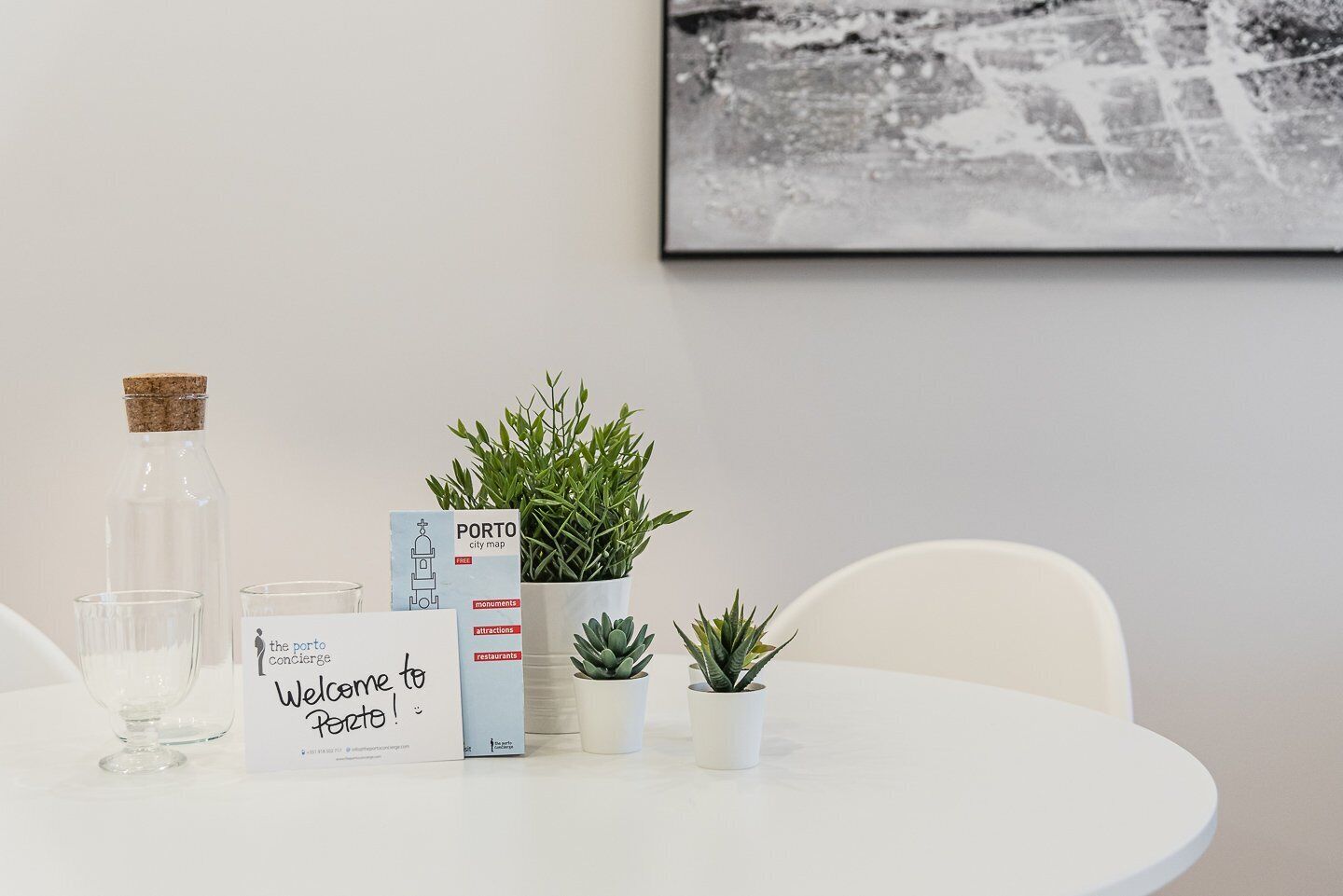 A table with a welcome sign, a city map, a glass bottle, and potted plants.
