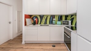 Eine kleine Küche mit weißen Schränken, einer Mikrowelle, einem Wasserkocher und einem Toaster.