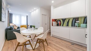 Eine moderne Wohnung mit Essbereich, einer Küche mit farbenfroher Spritzschutzleiste und einem Wohnbereich mit Sofa und Fernseher.