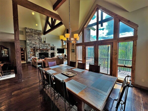 Enjoy meals in this inviting dining area with a large table, stone fireplace, and comfortable seating.