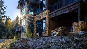 A large, multi-story wooden house with stone accents, large windows, and a stone fireplace. - Purgatory Cabin with Views and Hot Tub (Durango)