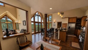 A spacious dining area with a wooden table, chairs, and a large window offering a view of the outdoors. - Purgatory Cabin with Views and Hot Tub (Durango)