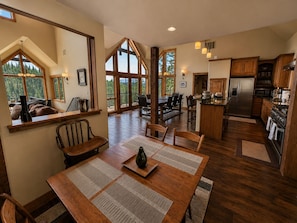 Uma sala de jantar espaçosa com mesa de madeira, cadeiras e uma grande janela com vista para o exterior.